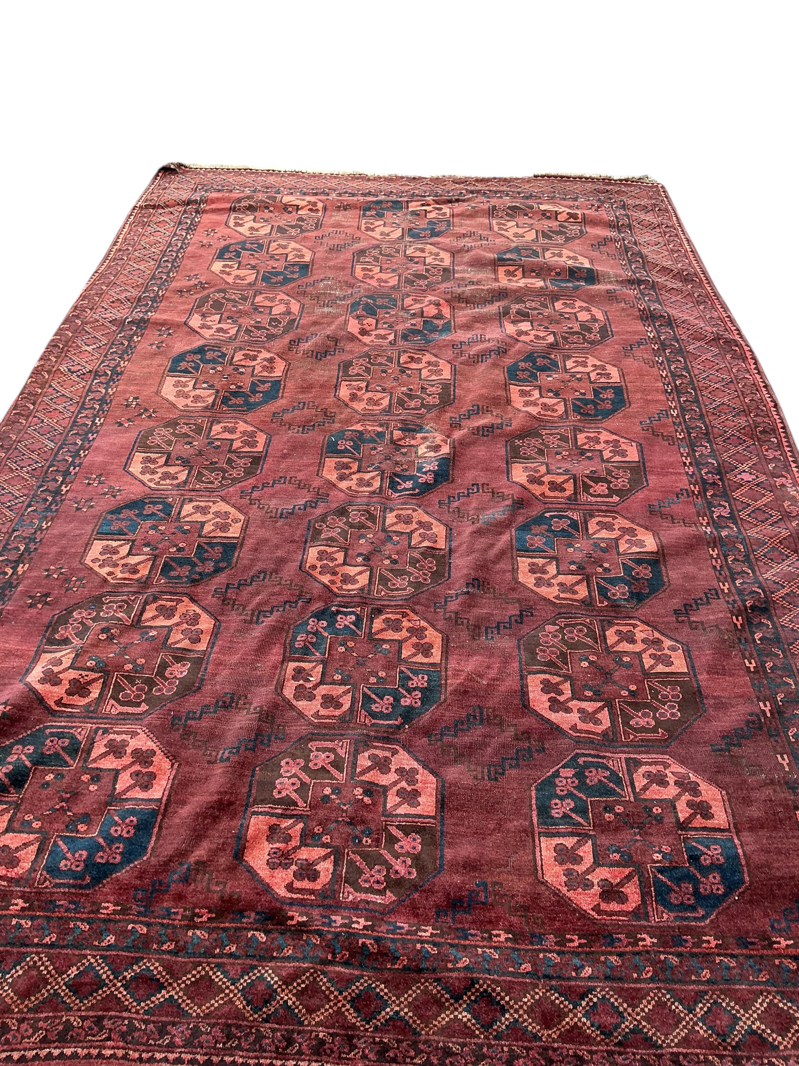An Afghan burgundy ground carpet, 375 x 230cm